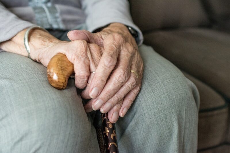 杖を手に座っている高齢女性